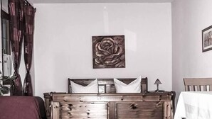Ein Schlafzimmer mit einem hölzernen Bett, einem kleinen Nachttisch, einem Beistelltisch, einem roten Teppich und einem Tisch mit weißer Tischdecke.