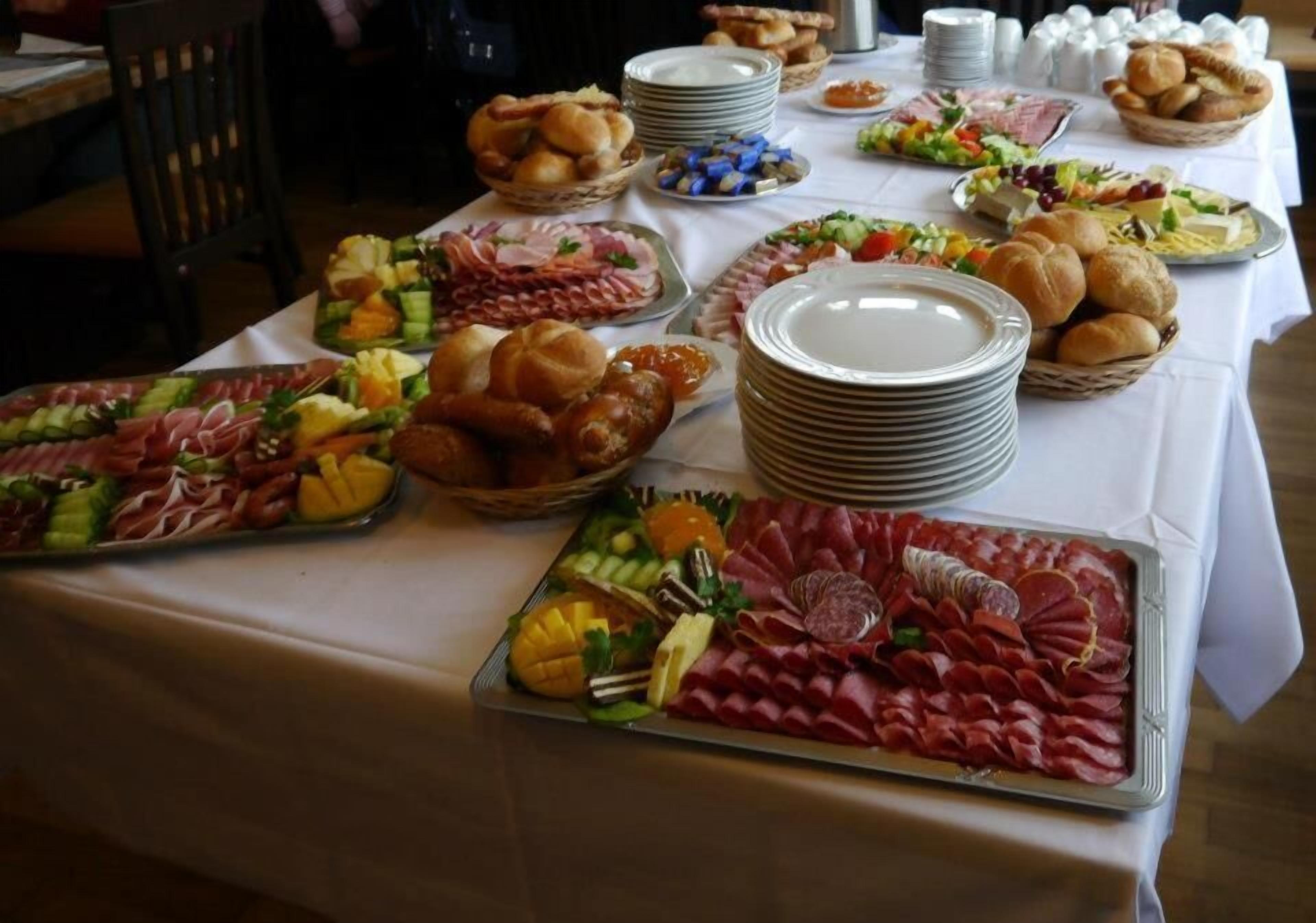 A buffet table with various food items and stacked plates.