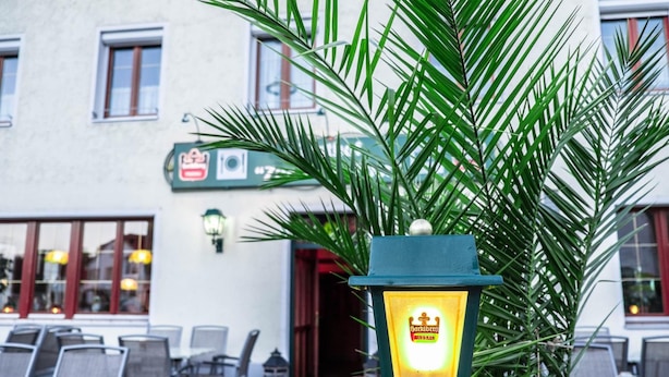 Ein Sitzbereich im Freien mit Stühlen und Tischen, einer Palme und einem beleuchteten Laternen