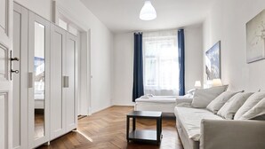 A modern living room with a sofa, a small table, and a bed with a white headboard. - Aparthotel Wenceslas (Prague)
