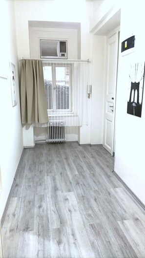 A hallway with a radiator, a window with curtains, and a door. - Aparthotel Wenceslas (Prague)