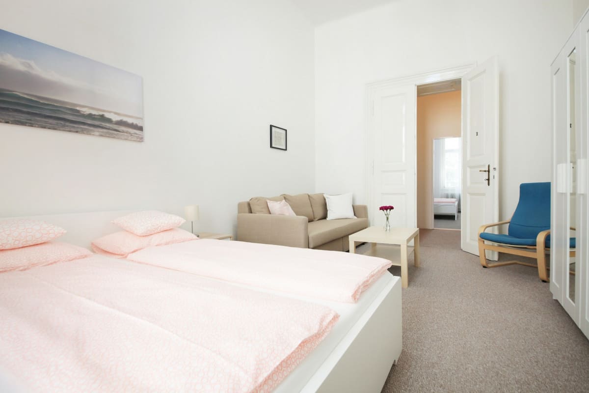 A hotel room with a bed, a sofa, a small table, and a chair.
