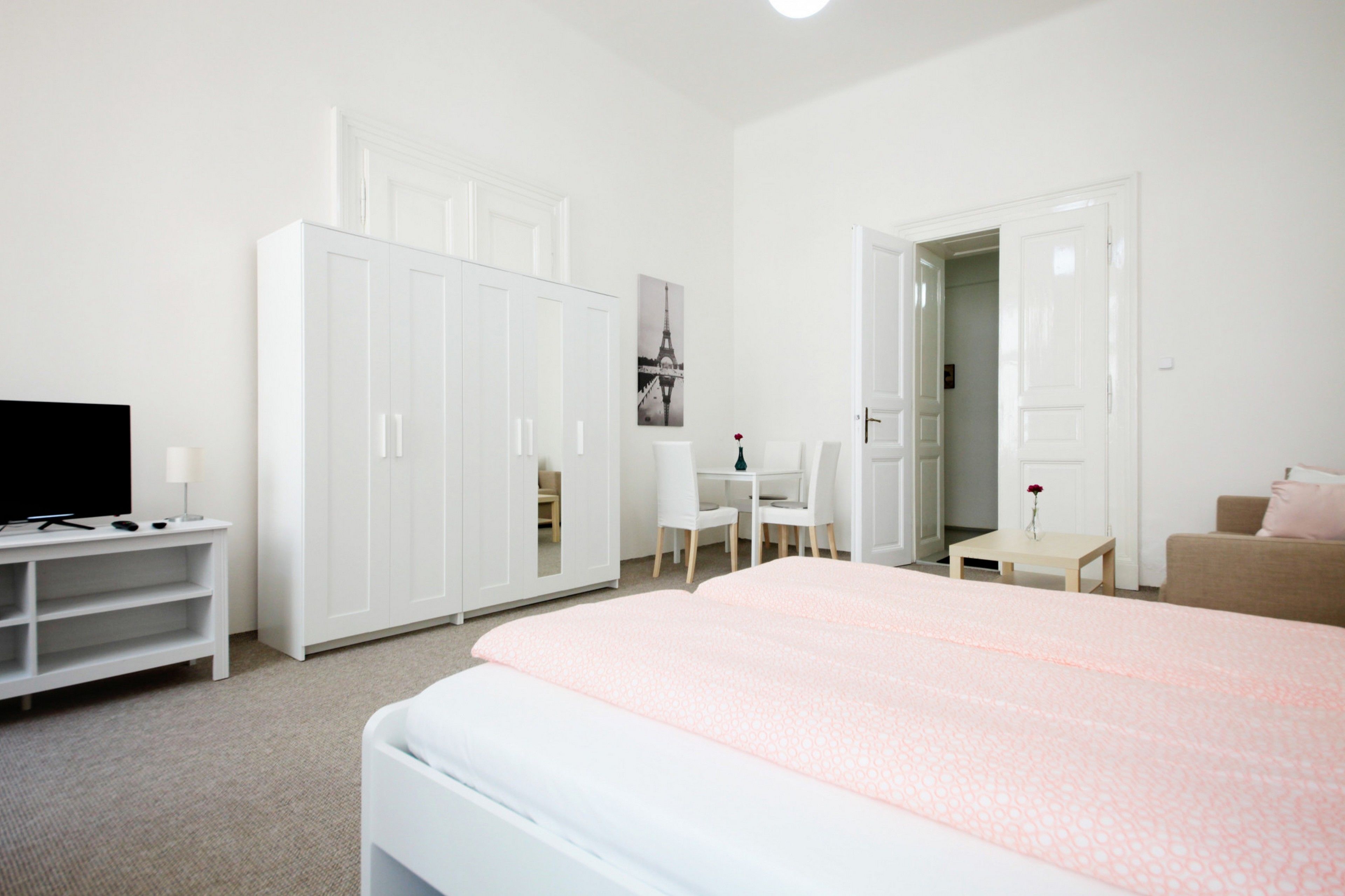 A bedroom with a bed, a TV, a wardrobe, a desk, and a chair.