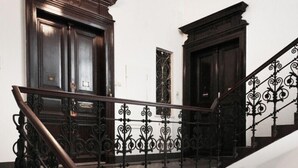 A staircase with ornate black railings and dark wooden doors at the top and bottom. - Aparthotel Wenceslas (Prague)