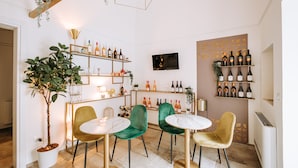 A modern interior with a bar area, green velvet chairs, and a variety of wine bottles on shelves. - Suite1212 Pirrelli (Monopoli)