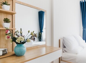 Quarto moderno com mesa de cabeceira de madeira, um vaso azul com flores e um espelho grande acima da mesa.