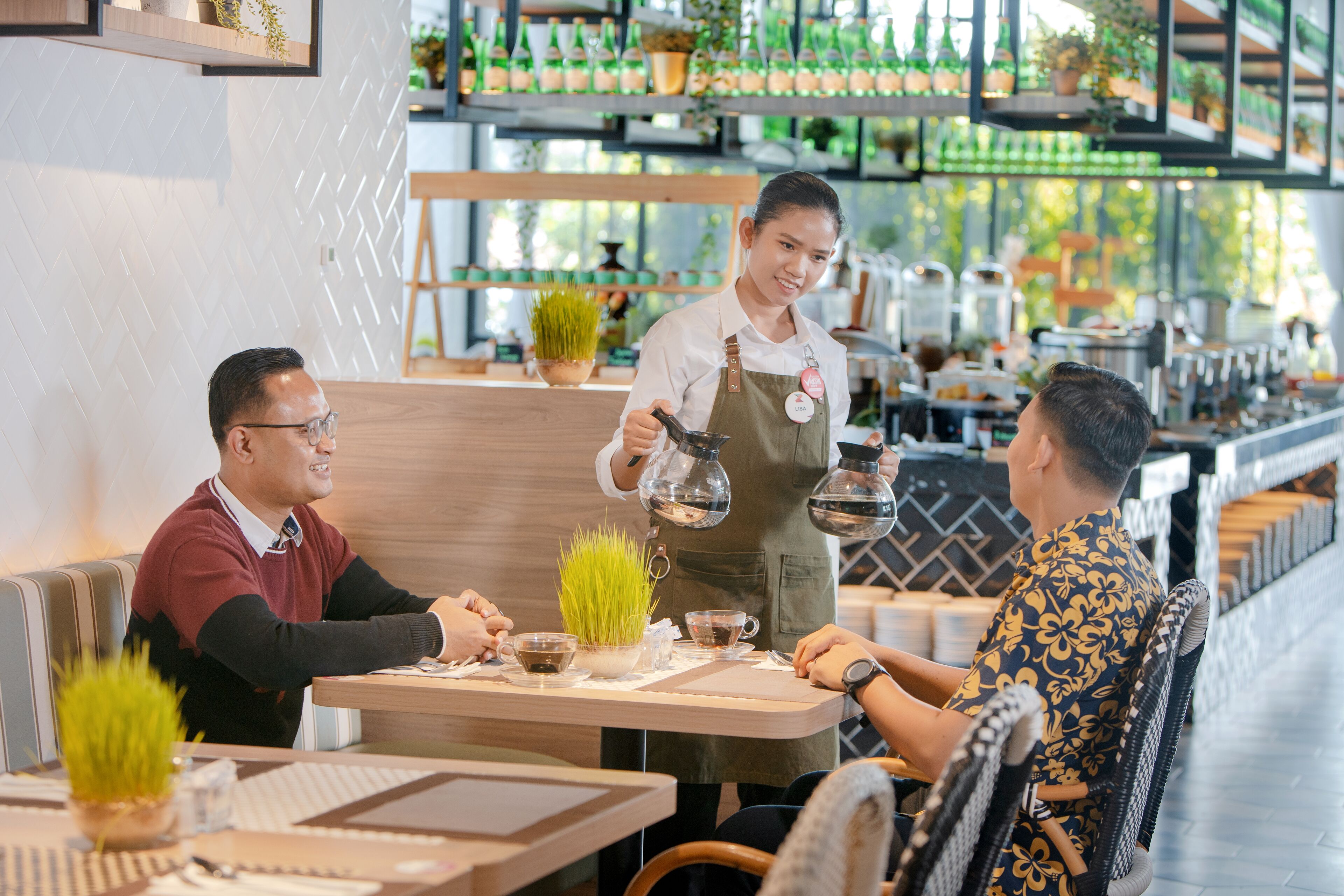 Un interior de restaurante con una zona de bar, asientos y una barra donde un camarero atiende a los clientes.