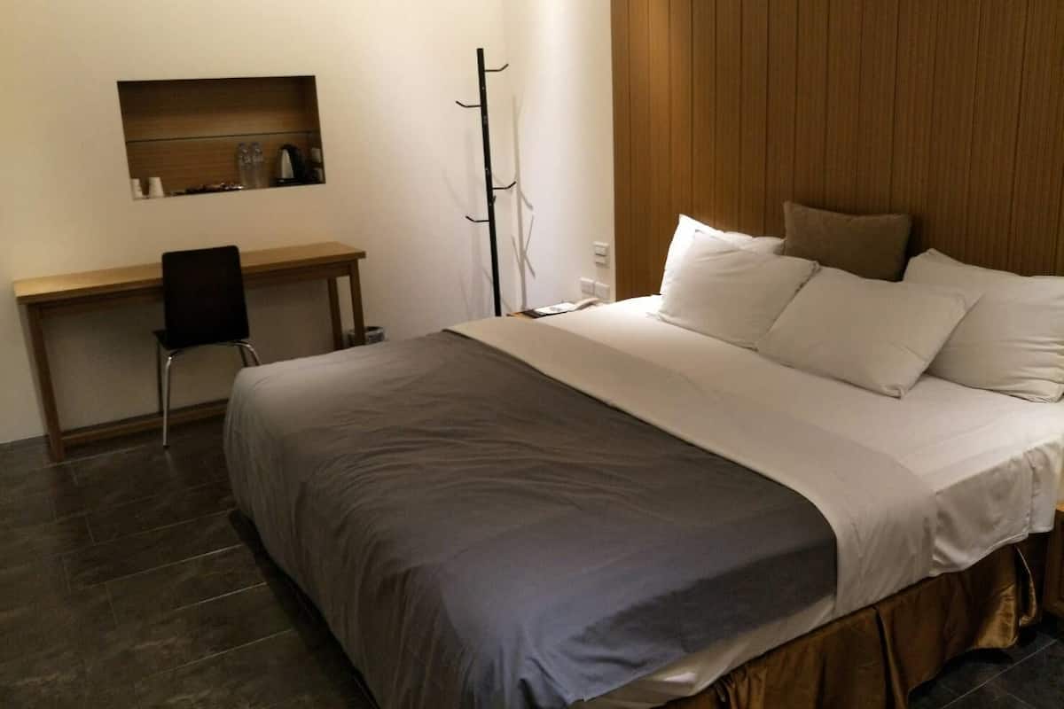 Una habitación de hotel con una cama, un escritorio y una silla.