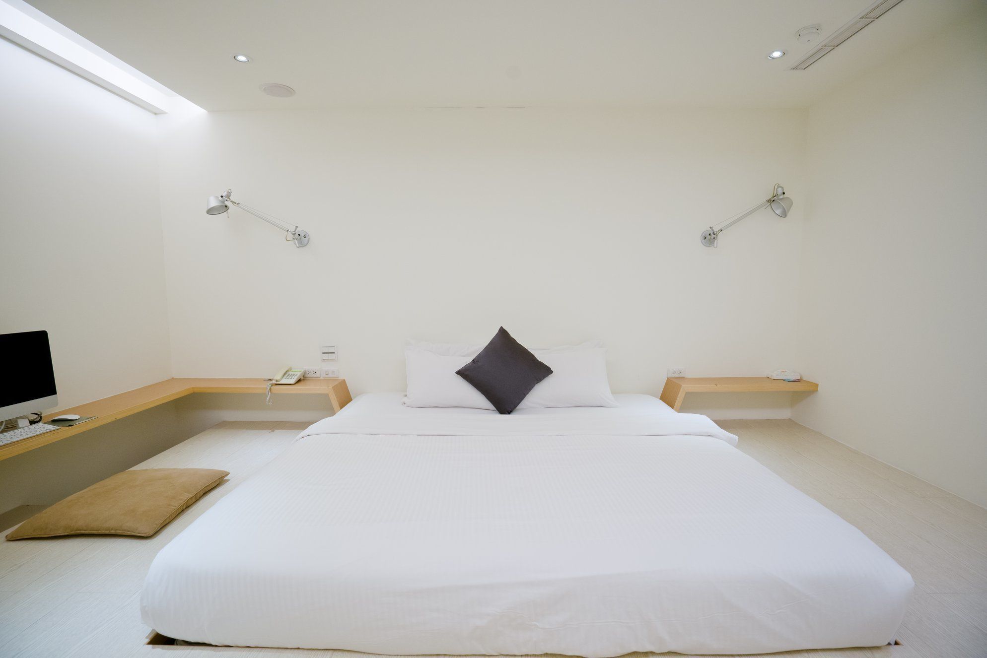 Una habitación de hotel moderna con una cama grande, mesitas de noche, un escritorio con computadora y lámparas de pared.