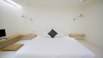 Una habitación de hotel moderna con una cama grande, mesitas de noche, un escritorio con computadora y lámparas de pared.