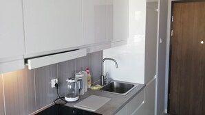 A modern kitchen with white cabinets, a stainless steel sink, a black induction cooktop, and a built-in oven.