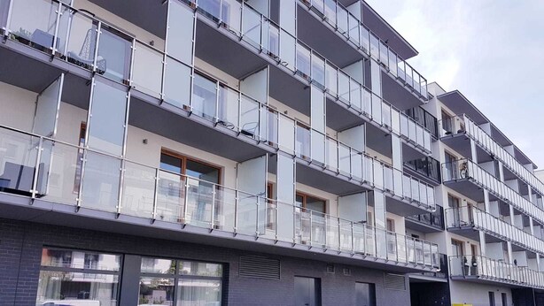 A multi-story residential building with balconies, large windows, and a brick facade.