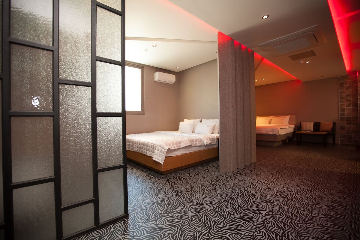 Una habitació d'hotel moderna amb un llit, zona de seients i un gran finestral.