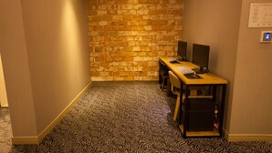 Un pasillo estrecho con pared de ladrillo, suelo a rayas de cebra y un escritorio con computadora y altavoces.