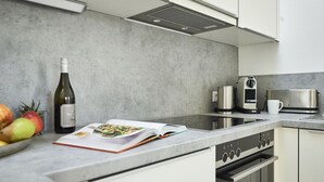 Una cocina moderna con horno empotrado, cafetera, tostadora y un bol de fruta.