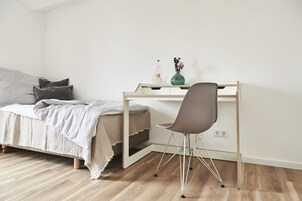 Un dormitorio con cama, escritorio y silla.