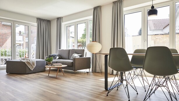 Una sala de estar moderna con un sofá, una mesa de centro y un comedor con sillas.