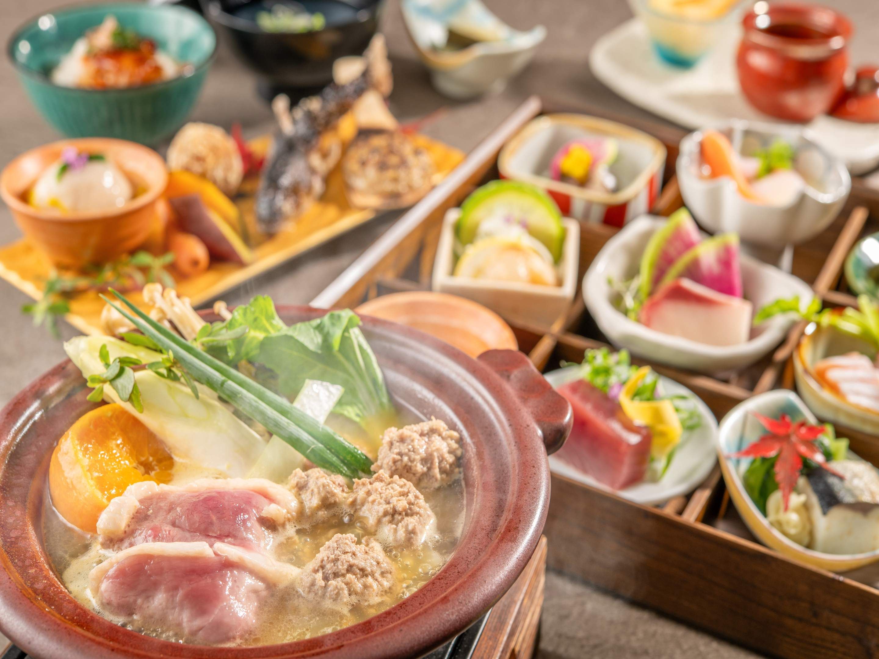 A variety of dishes including a hot pot with meatballs and vegetables, and several small bowls with different foods.