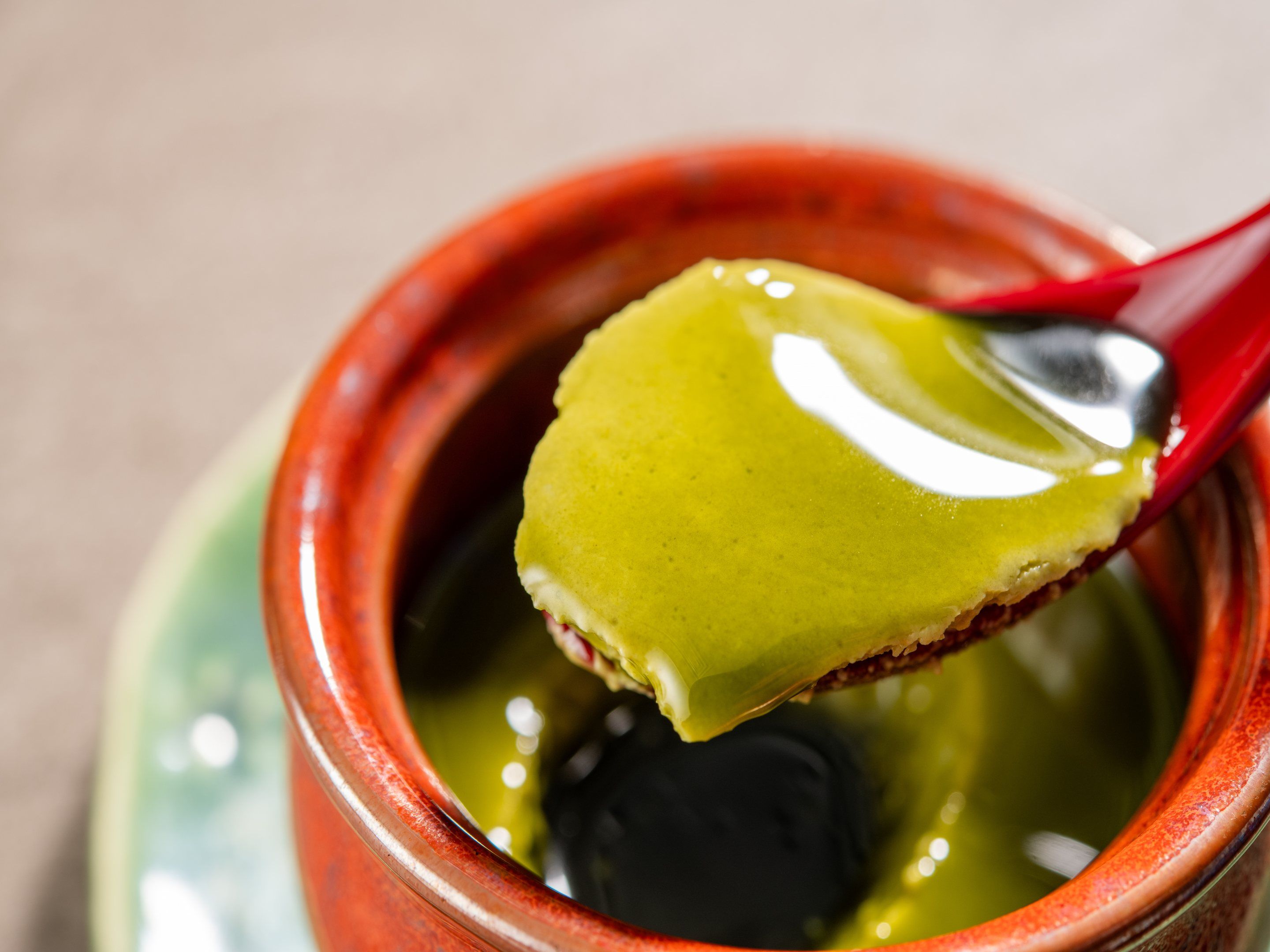 A spoonful of yellow food being lifted from a ceramic bowl.
