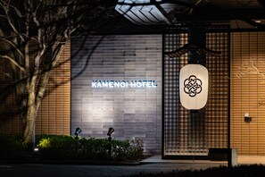L’entrée d’un hôtel, avec une façade moderne, une enseigne bien visible et une lanterne de style traditionnel.