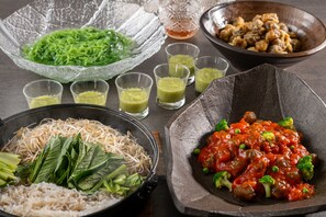 Un assortiment de plats comprenant des nouilles, des légumes verts et de la viande, le tout servi dans un bol.