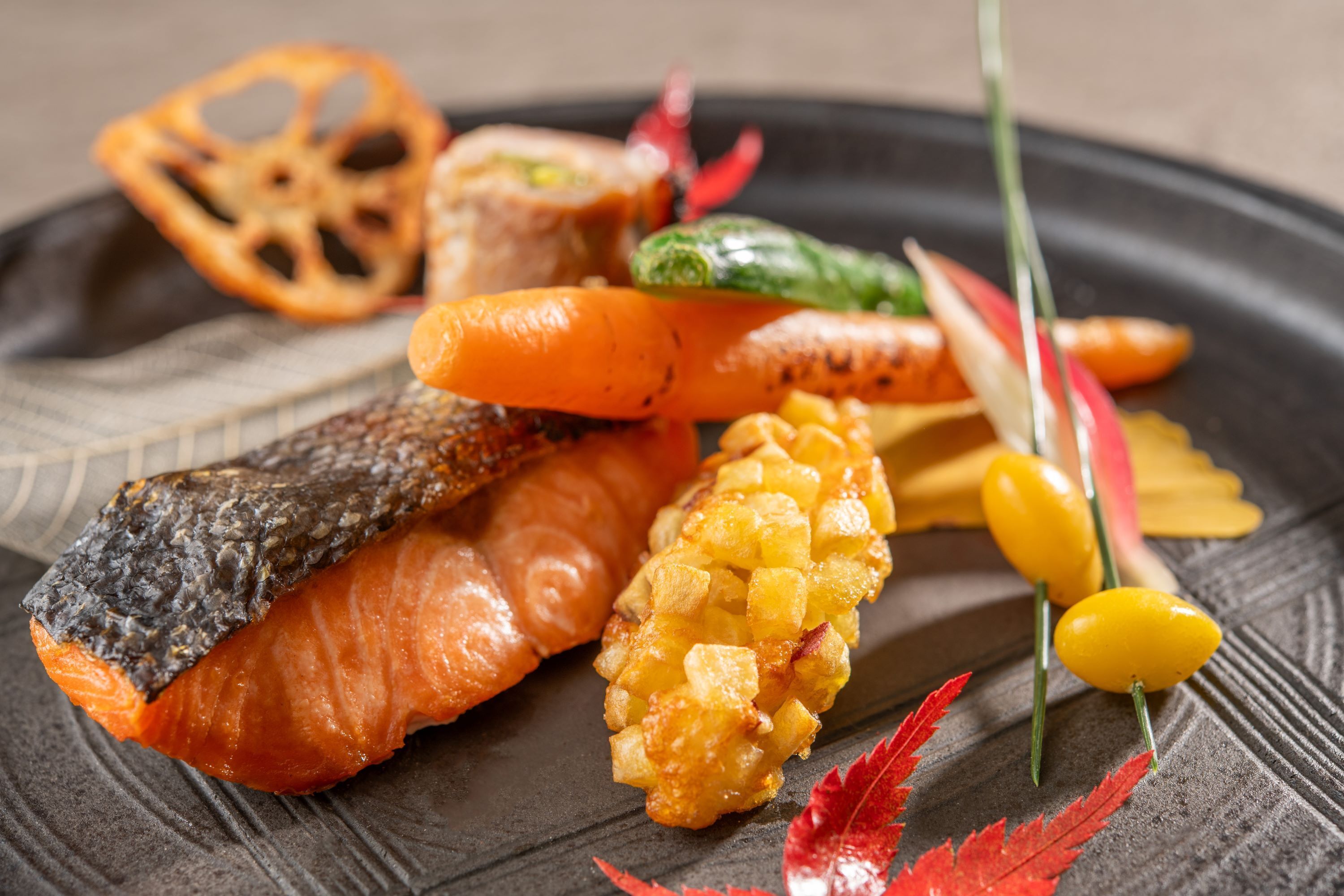 A plate with various food items including a piece of fish, vegetables, and a decorative element.