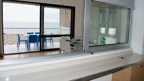 A balcony with a table and chairs, overlooking a beach. - Appartamento Augustus (Jesolo)
