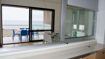 Un balcón con mesa y sillas, con vista a la playa.