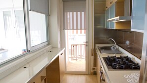 A modern kitchen with a gas stove, a sink, and wooden cabinets. - Appartamento Augustus (Jesolo)