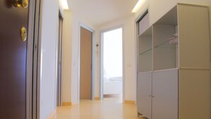 A hallway with a wooden floor, a wardrobe, and a door leading to a room. - Appartamento Augustus (Jesolo)
