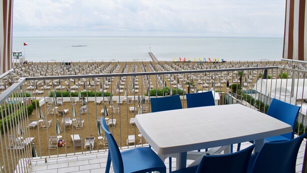 A balcony with a view of a beach with rows of sun loungers and umbrellas. - Appartamento Augustus (Jesolo)