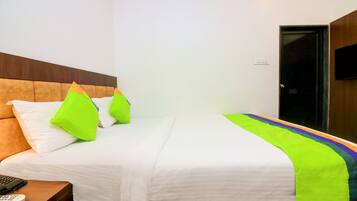 A hotel room with a bed, pillows, a blanket, a remote control, and a door.