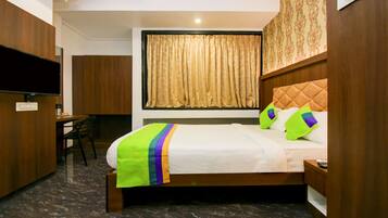 Una habitación de hotel con cama, escritorio, silla y televisor.