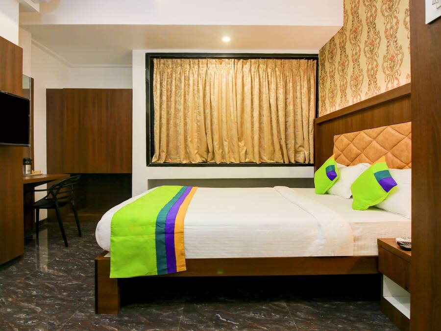 Una habitación de hotel con cama, escritorio, silla y televisor.