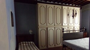 A bedroom with a bed, a bench, a wardrobe, and a chandelier. - Affittacamere Ferrari (Pescaglia)