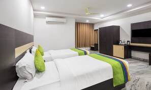 A hotel room with two beds, a desk, a wardrobe, and a flat-screen TV.
