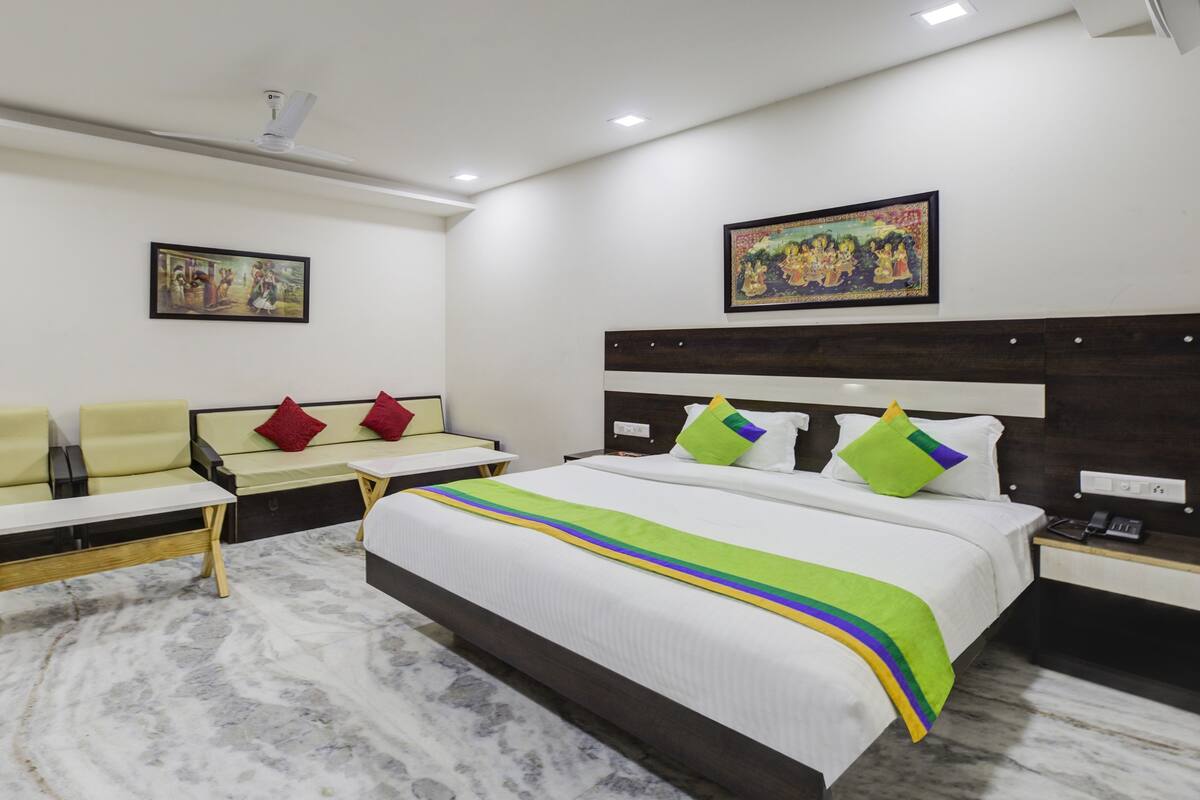 A hotel room with a bed, a sofa, a small table, and a nightstand.