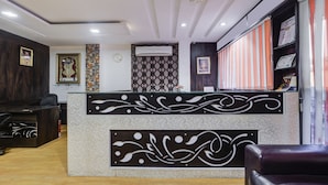 A reception area with a modern design, including a patterned wall, a clock, and a reception desk with decorative elements. - Treebo Trend Royal Dizire (Udaipur)