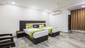 A hotel room with two beds, a ceiling fan, an air conditioning unit, and a marble floor. - Treebo Trend Royal Dizire (Udaipur)