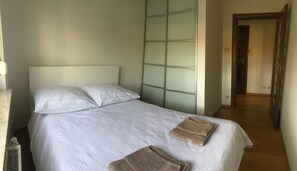 A neatly made bed with white linens and two folded towels on the foot of the bed. - Apartament F&J 12 (Torun)