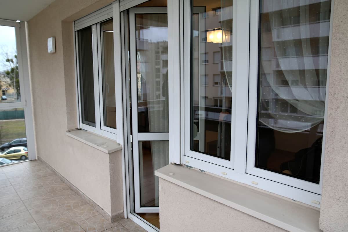 A corner of a building with large windows and a small window ledge.