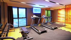 Un gimnasio moderno con cintas de correr, una banca y mancuernas.