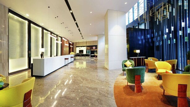 Un vestíbulo de hotel moderno con mostrador de recepción, zona de estar y un amplio ventanal.