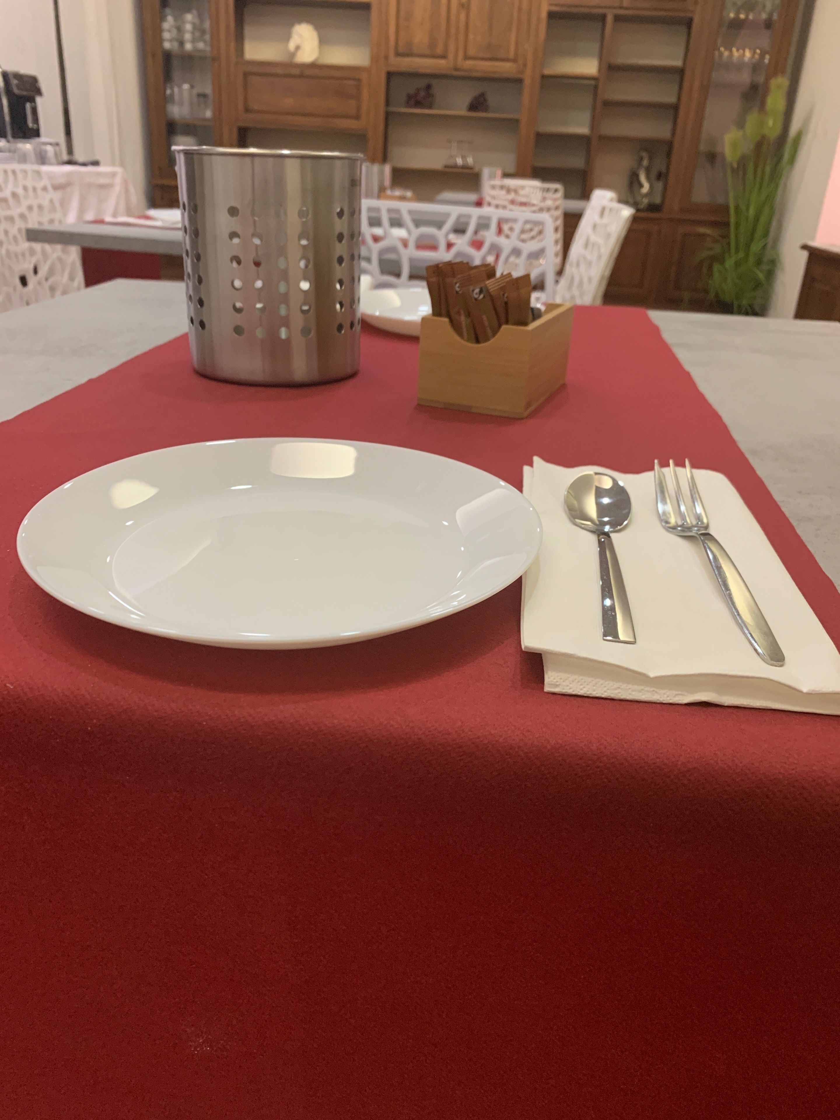 Uma mesa de jantar com um prato branco, um escorredor de metal e um guardanapo com talheres.