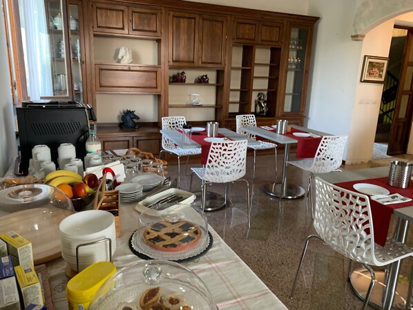Un comedor con mesas y sillas, una barra de buffet y una zona de cocina al fondo.