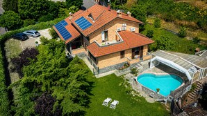 Une maison avec une piscine, des panneaux solaires et une serre.