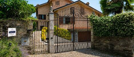 A villa with a stone wall, a metal gate, and a sign indicating a restaurant.