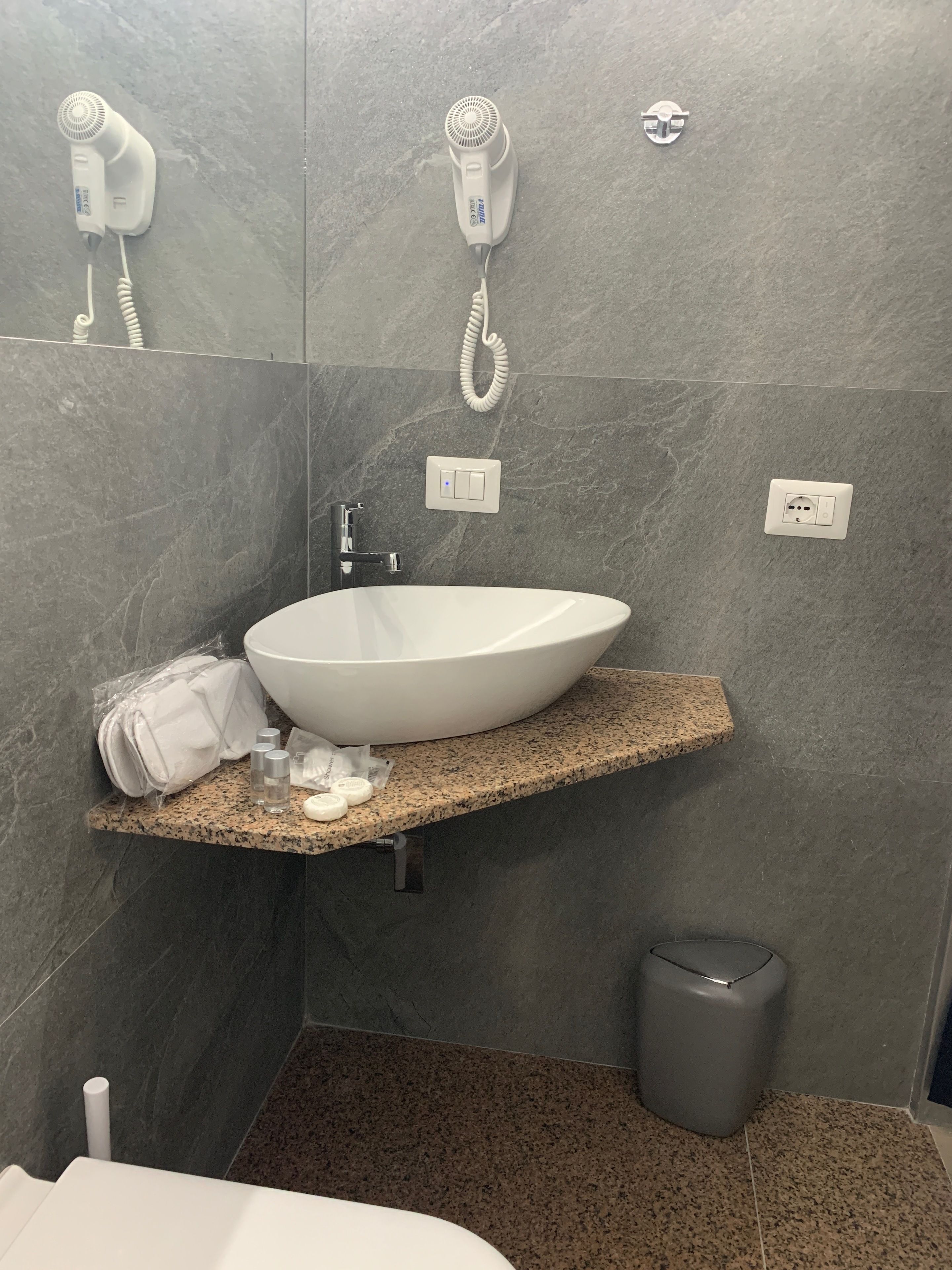 A bathroom with a white sink, a towel, and a hairdryer on a granite countertop.