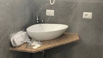 A bathroom with a white sink, a towel, and a hairdryer on a granite countertop.