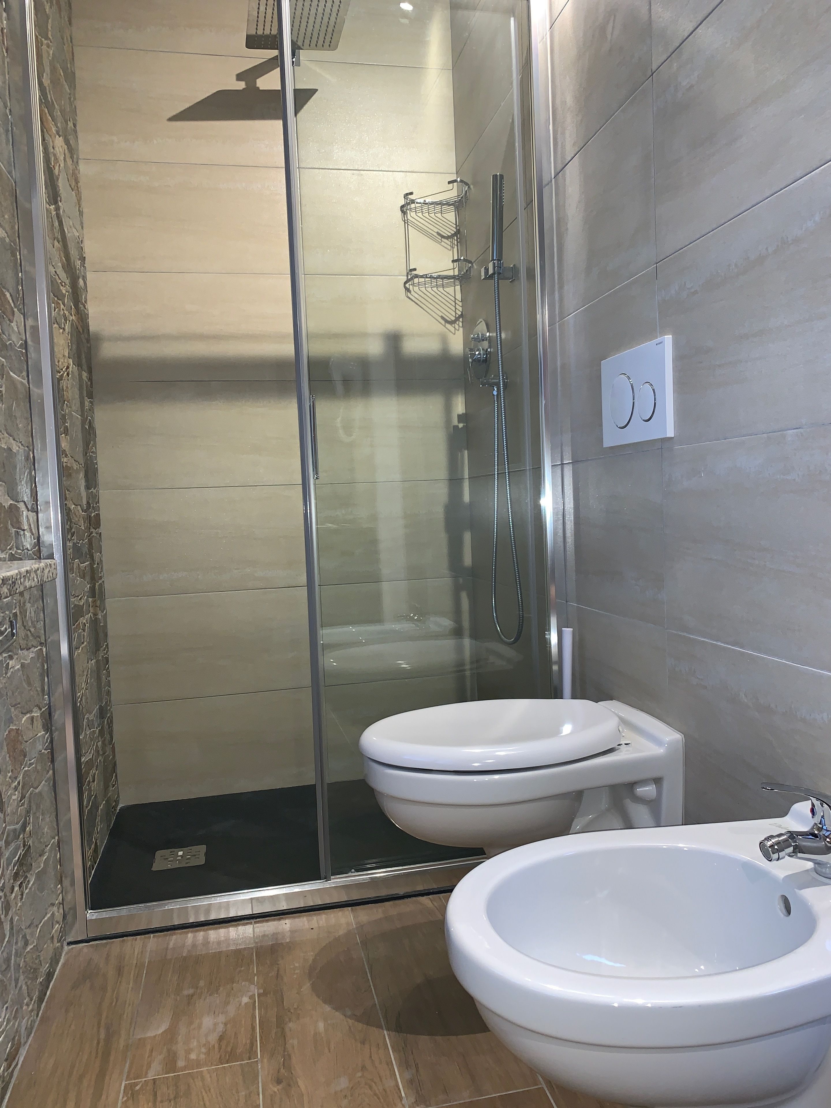 Une salle de bain moderne dotée d’une douche à parois de verre, de toilettes et d’un bidet.